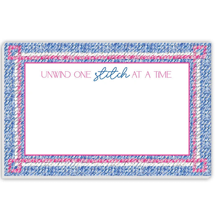 A square white card or coaster with a decorative border made of blue and pink stitched-look texture. The top center reads 'UNWIND ONE stitch AT A TIME' in pink and blue script, with a large blank white space below.