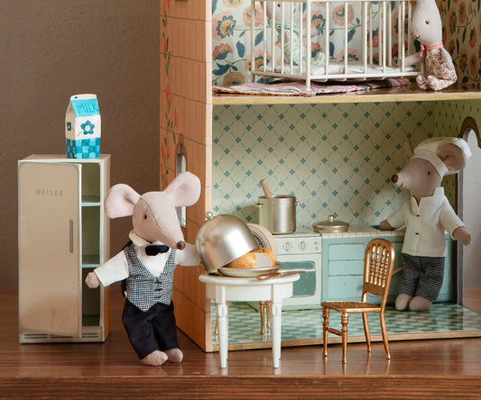 Miniature mouse characters in a kitchen setting with a refrigerator and dining table.