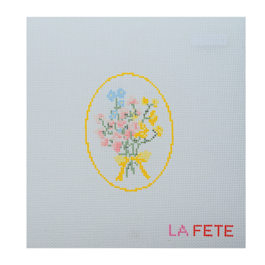 needlepoint design of a floral bouquet with a yellow bow on light blue fabric, featuring the text 'LA FETE'.