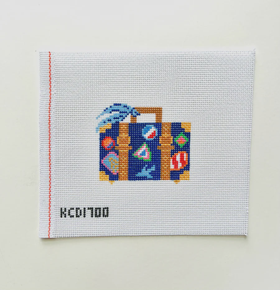Cross-stitched design of a suitcase with colorful patterns on a white background