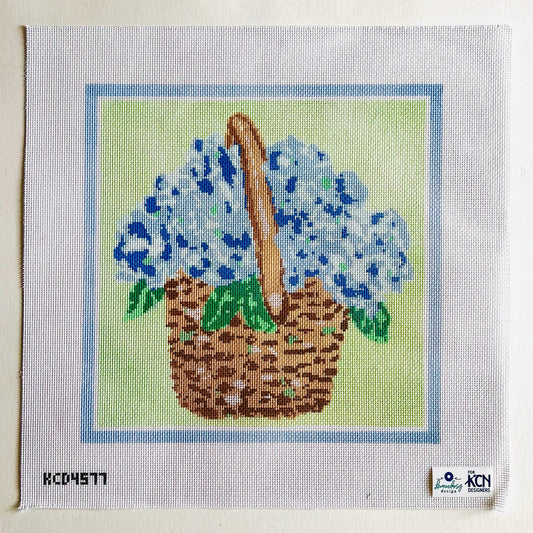 Cross-stitched design of a basket with blue flowers on fabric.