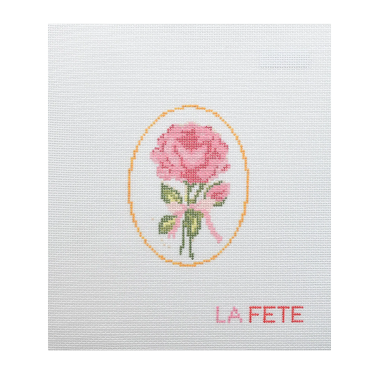 Cross-stitched design of a pink rose with a yellow border on white fabric, featuring the word 'LA FETE'.