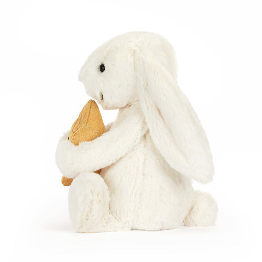 White plush bunny holding a carrot on a white background