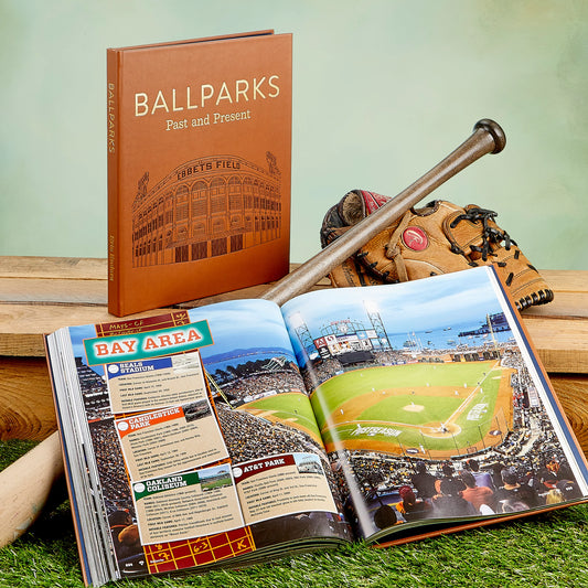 Book titled 'Ballparks: Past and Present' with a baseball bat, glove, and open book showing stadium images on grass.
