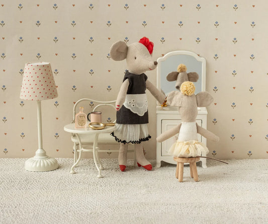 Two toy mice in a room with a lamp, table, and mirror.