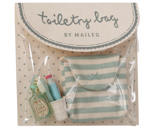 Toiletry bag set by Maileg in clear plastic packaging with a beige polka-dot backing card. The set includes a small striped mint green and cream pouch, a miniature green toiletry bottle labeled 'Tirra Loci', a small white cup, and a miniature toothbrush.