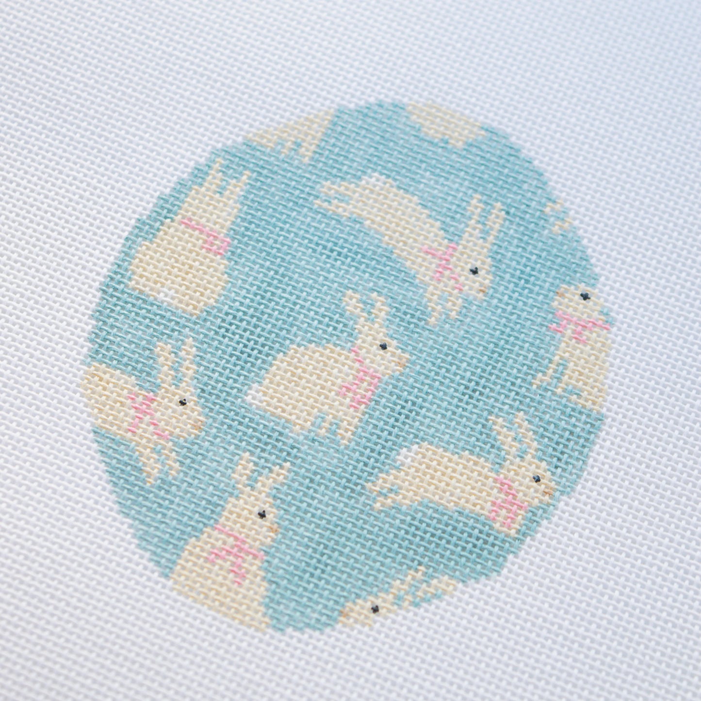 needlepoint pattern of bunnies on a light blue background
