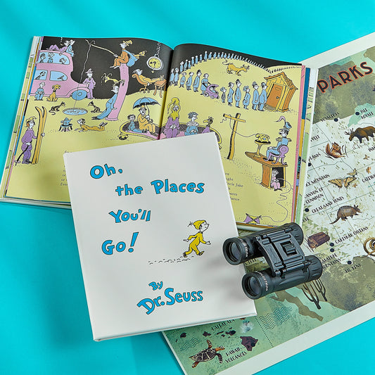 Open book with illustrations, 'Oh, the Places You'll Go!' by Dr. Seuss, and binoculars on a blue background