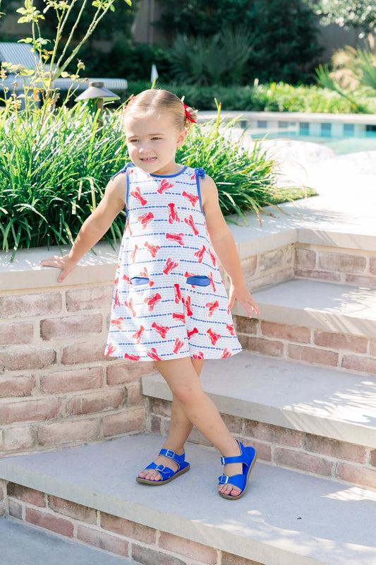 Young girl in a patterned dress standing on steps outdoors