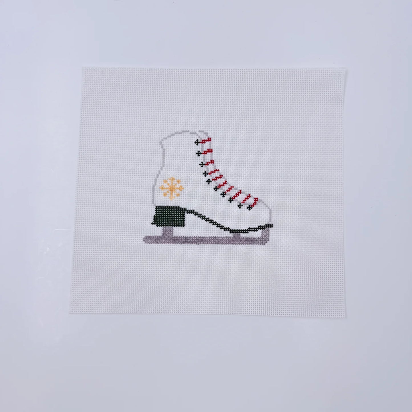Cross-stitched ice skate on a white fabric background