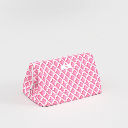 Pink and white geometric patterned wedge shaped cosmetic bag on a light gray background