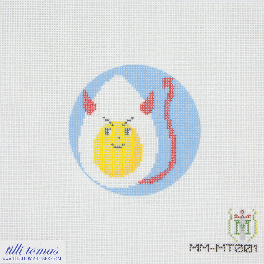 Cross-stitched design of a cartoonish egg with a face on a light gray background, featuring the brand 'tillitomas'.