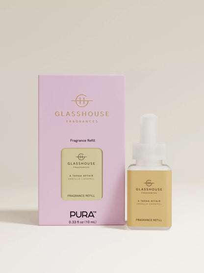A fragrance refill bottle with a white dropper cap stands beside its light pink retail box. The bottle has a pale yellow label reading GLASSHOUSE FRAGRANCES, and the box is lavender with gold text and a matching yellow label panel.