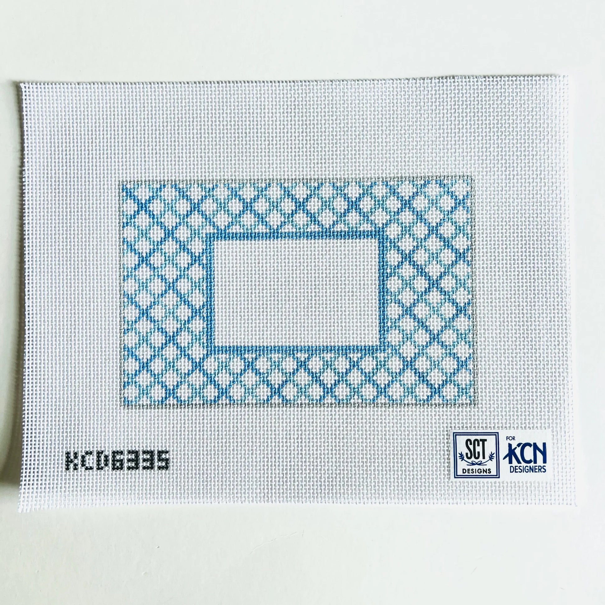 Cross-stitch pattern on fabric with blue and white design, KCDN logo visible