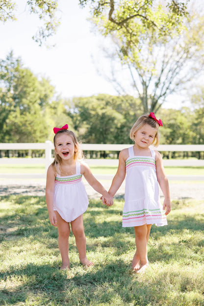 two children in white dresses hold hands outside