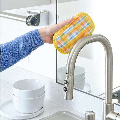 Person using a colorful scrubber to clean a kitchen faucet.