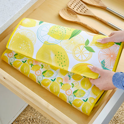 Roll of lemon-patterned paper towel on a wooden surface with hands interacting with it.