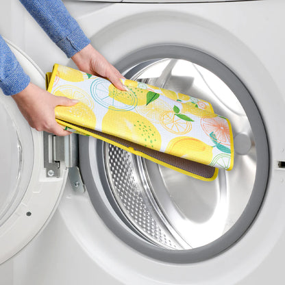 Person holding a colorful towel with lemon design in front of a washing machine.