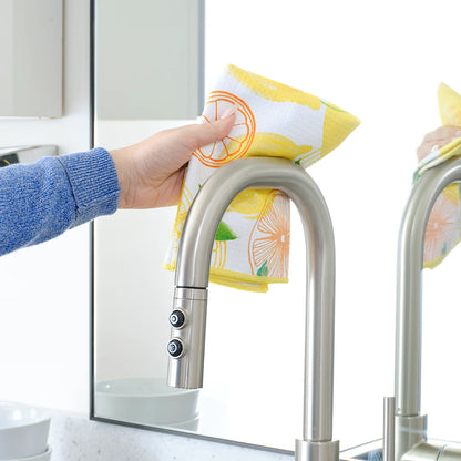 Person cleaning a kitchen faucet with a yellow and white dishcloth.