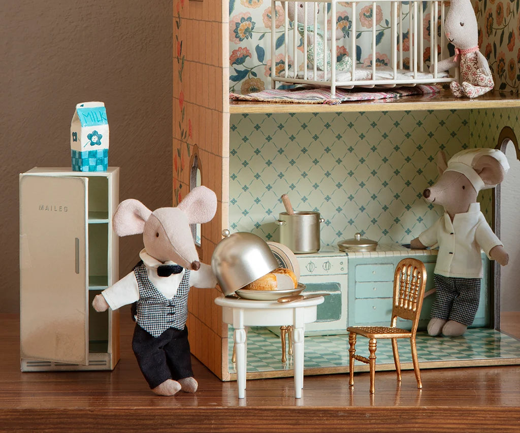 Miniature mouse characters in a kitchen setting with a refrigerator and dining table.