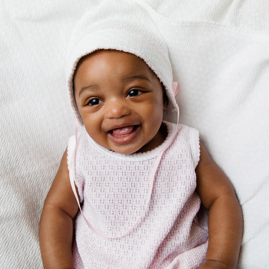 Baby wearing a pink towel on a white background