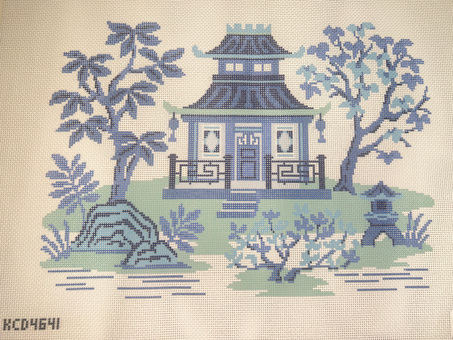Embroidered design of a blue pagoda with trees and garden elements on a beige background.