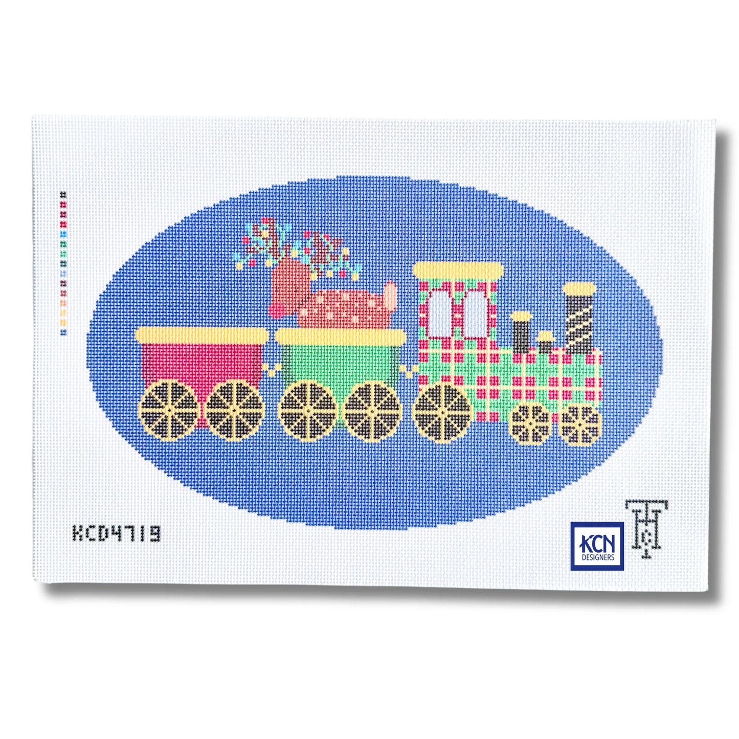 A needlepoint canvas featuring a colorful Christmas train design. The train has pink, green, and plaid red-and-white carriages with gold wheels, set against a blue oval on a white canvas background.