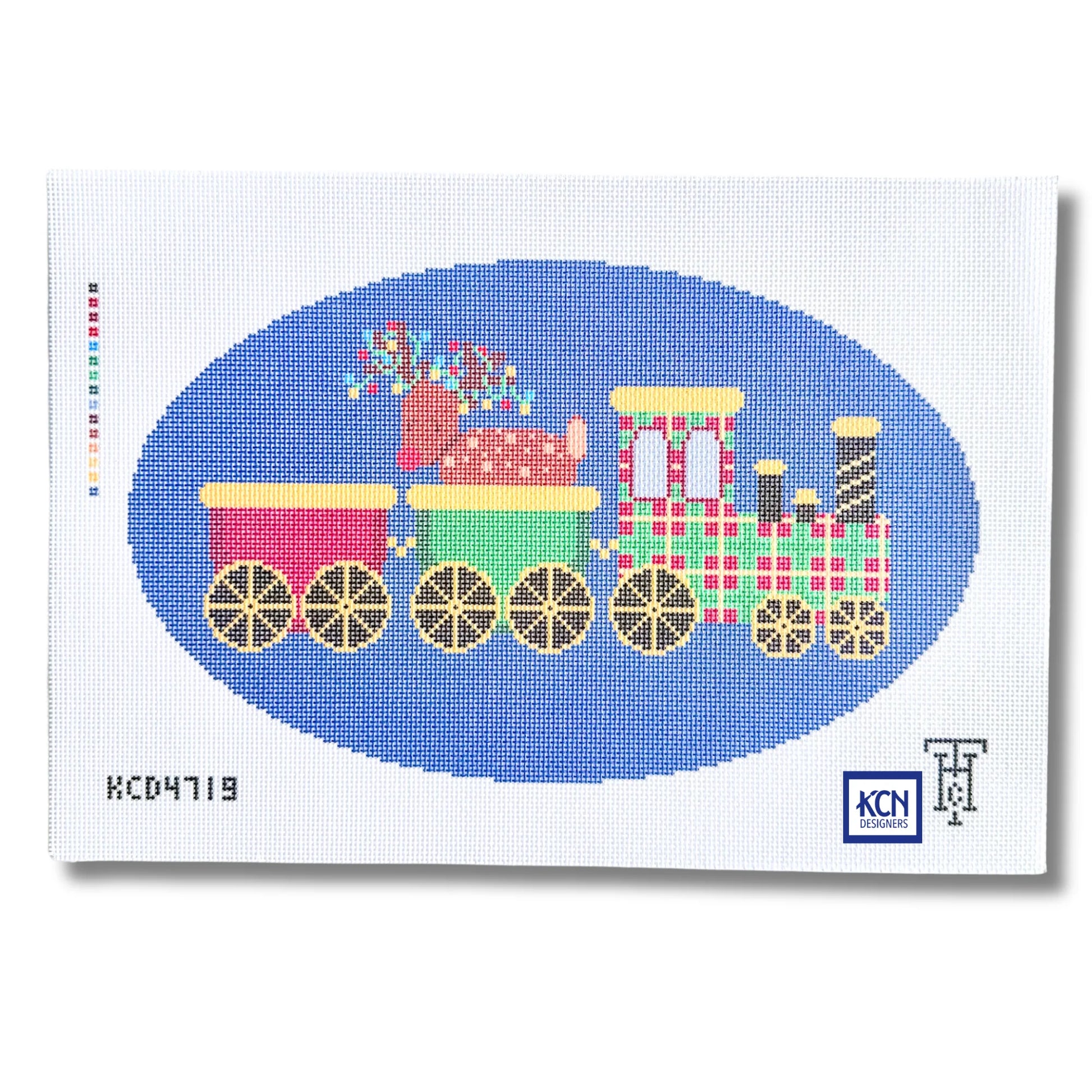 A needlepoint canvas featuring a colorful Christmas train design. The train has pink, green, and plaid red-and-white carriages with gold wheels, set against a blue oval on a white canvas background.