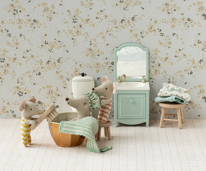 Children's bathroom set with toy mice, sink, and bathtub against floral wallpaper.