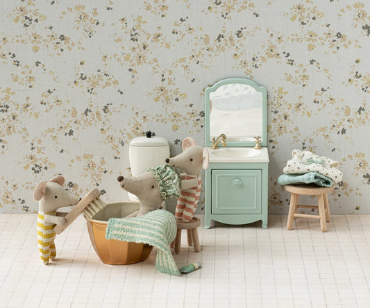 Children's bathroom set with toy mice, sink, and bathtub against floral wallpaper.