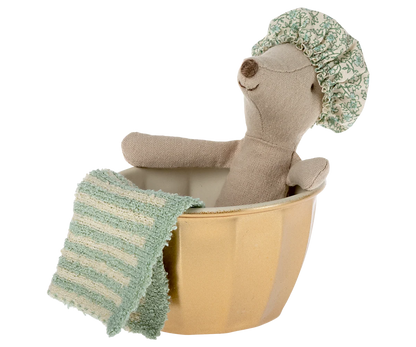 Plush toy bear in a bathtub with a green towel and shower cap on a white background