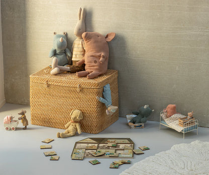 Wicker toy box with plush toys and children's furniture in a room.