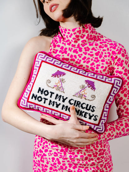 Person wearing a pink leopard print dress holding a pillow with 'Not my circus, not my monkeys' text.
