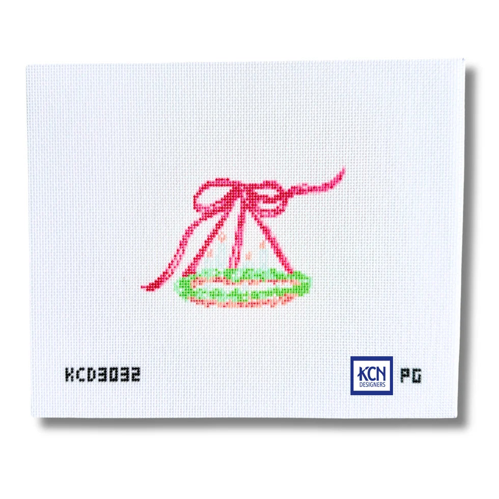 A square white needlepoint canvas featuring a hand-stitched design of a hanging chandelier with a red ribbon and green trim, with product codes 'KCD3032' and 'KCN PG' printed on the canvas.