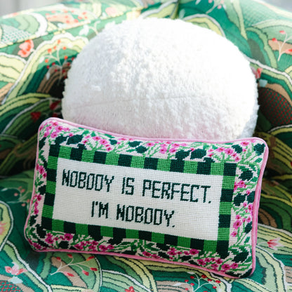 Decorative pillow with 'Nobody is perfect, I'm nobody' text on a floral fabric background