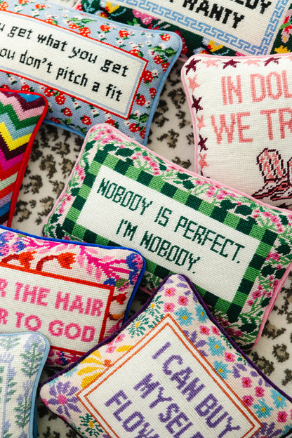 Decorative pillows with embroidered text on a patterned fabric background