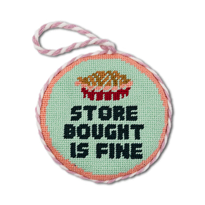 Round cross-stitched pendant with text on a white background