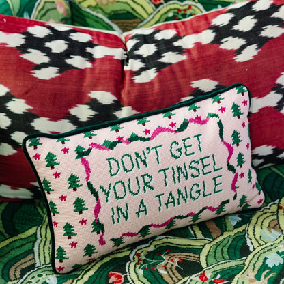 Decorative pillow with Christmas-themed text and patterns on a colorful fabric background