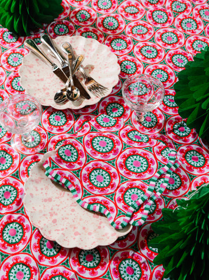 Decorative table setting with a red and green patterned tablecloth, plates, and cutlery.
