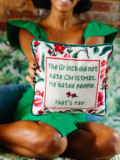 Person holding a decorative pillow with a Grinch quote against a blurred background