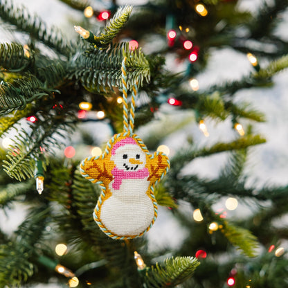 Decorative snowman ornament on a Christmas tree with lights in the background