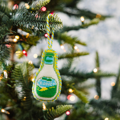Decorative ornament shaped like a bottle with a yellow cap, hanging on a Christmas tree.