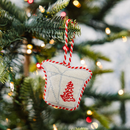 Decorative Christmas ornament with red tree design on a Christmas tree.