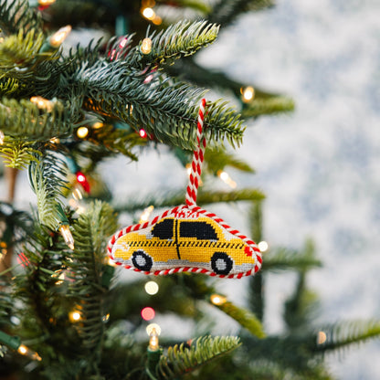 Decorative yellow taxi ornament on a Christmas tree with lights.