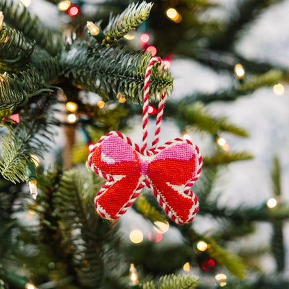 Red and pink bow-shaped ornament on a Christmas tree with blurred lights in the background