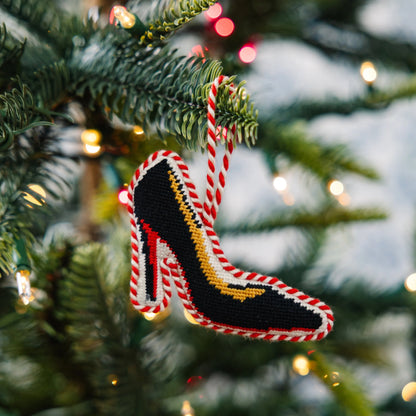 Decorative high-heeled shoe ornament on a Christmas tree with lights in the background