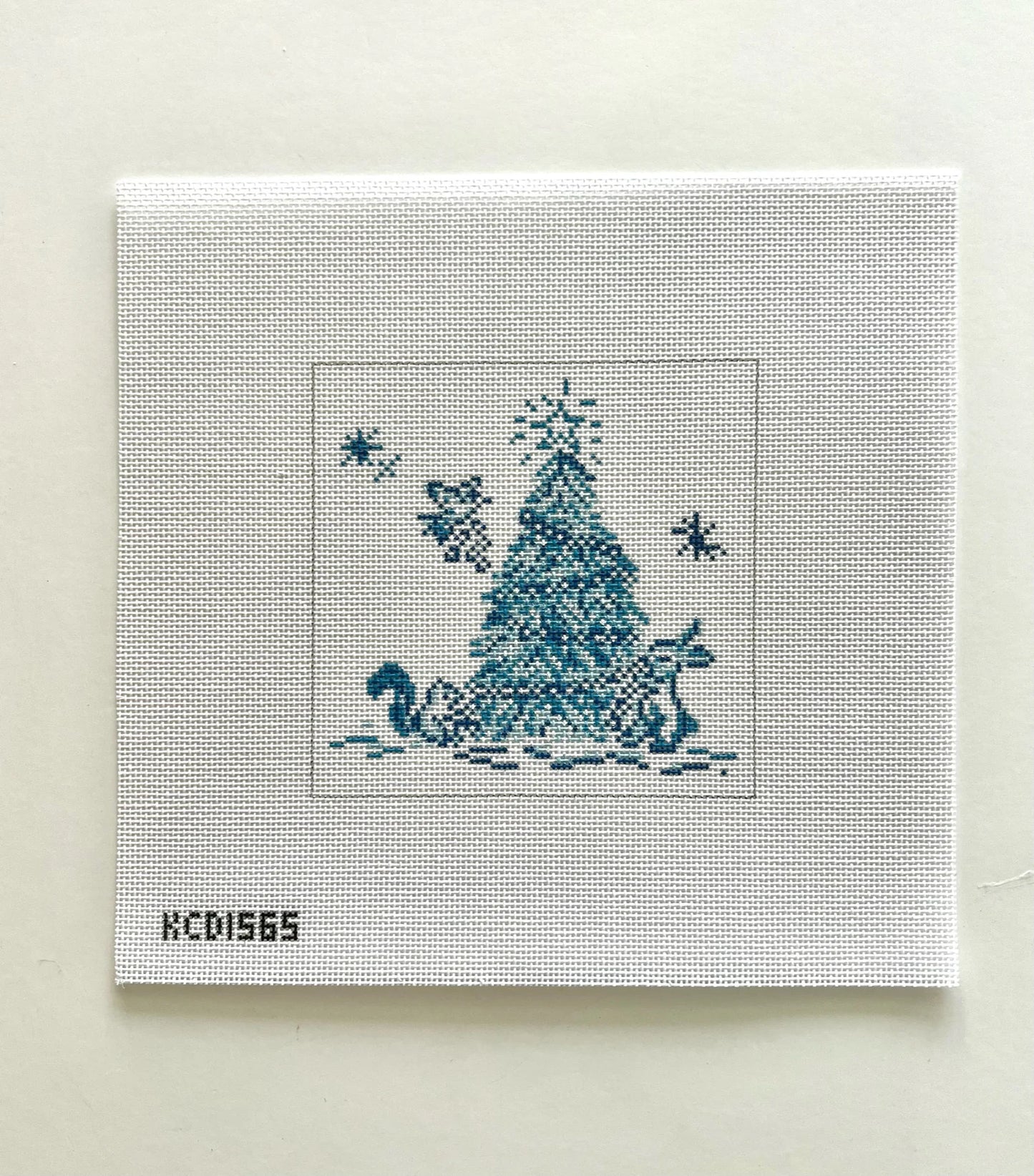 Cross-stitched design of a Christmas tree and swan on fabric with 'KCD1565' label.
