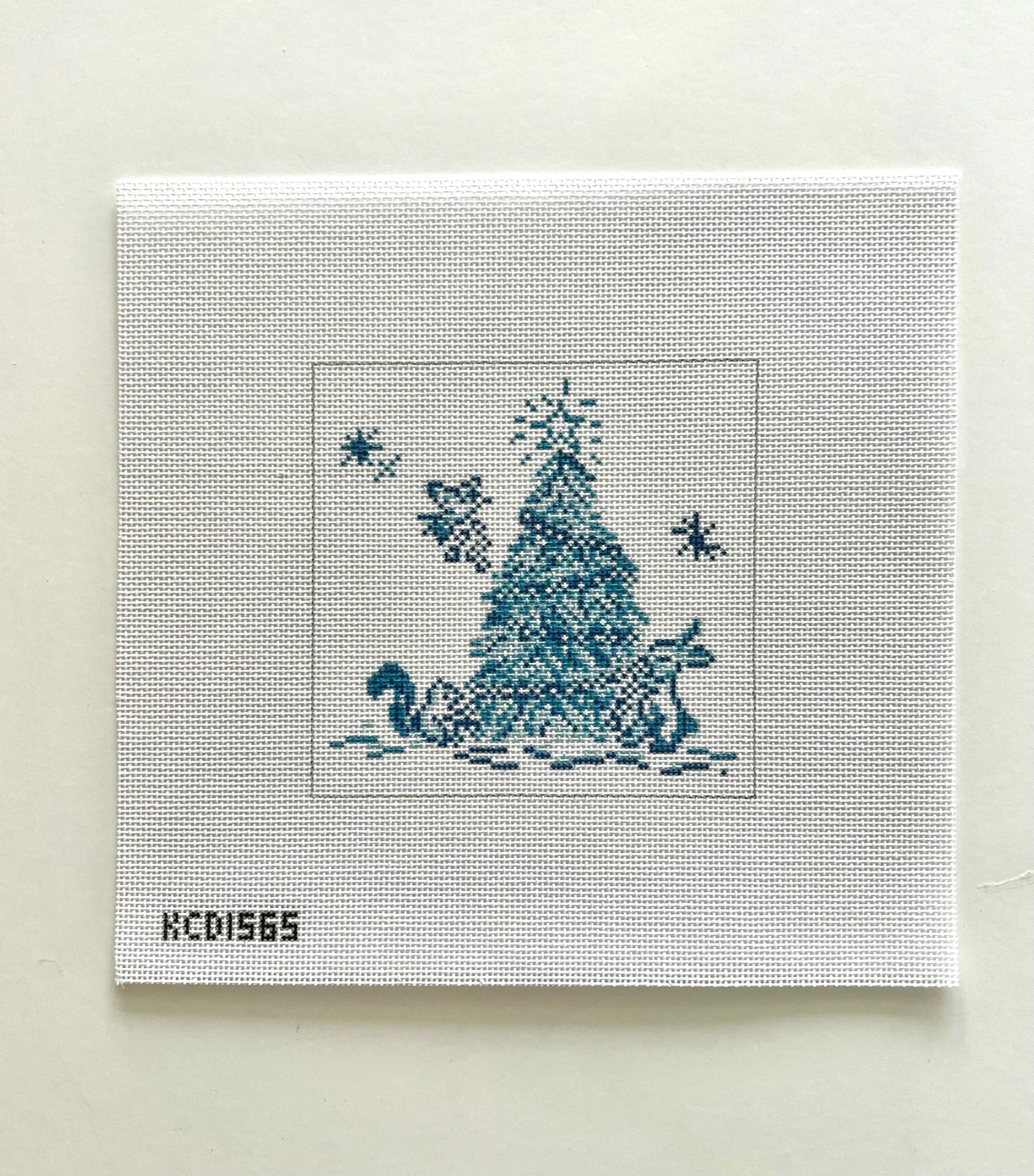 Cross-stitched design of a Christmas tree and swan on fabric with 'KCD1565' label.