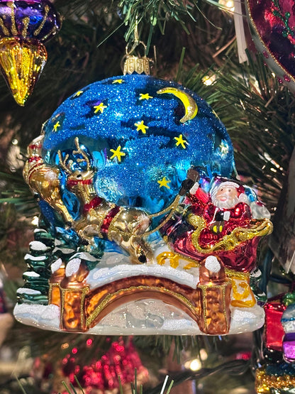 Decorative Christmas ornament with Santa Claus and reindeer on a tree.