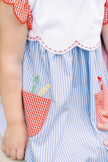 Child wearing a blue and white striped dress with red checkered accents